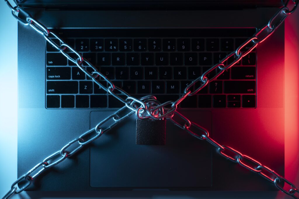Laptop zabezpieczony łańcuchem i kłódką – symbol fizycznej blokady dostępu do sieci.